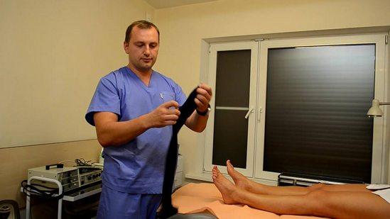 Doctor putting compression stockings on a patient